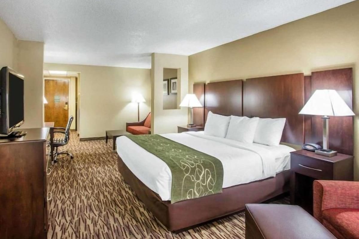 Une chambre d’hôtel avec un grand lit, des tables de chevet, un bureau, une chaise et un téléviseur.