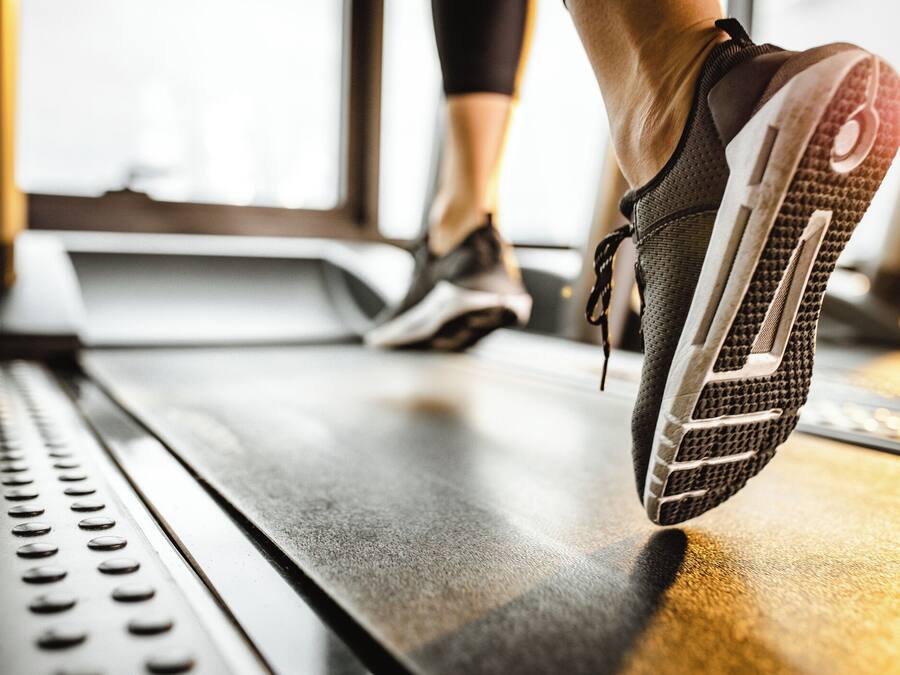 Primer plano de un zapatilla deportiva sobre una cinta de correr.