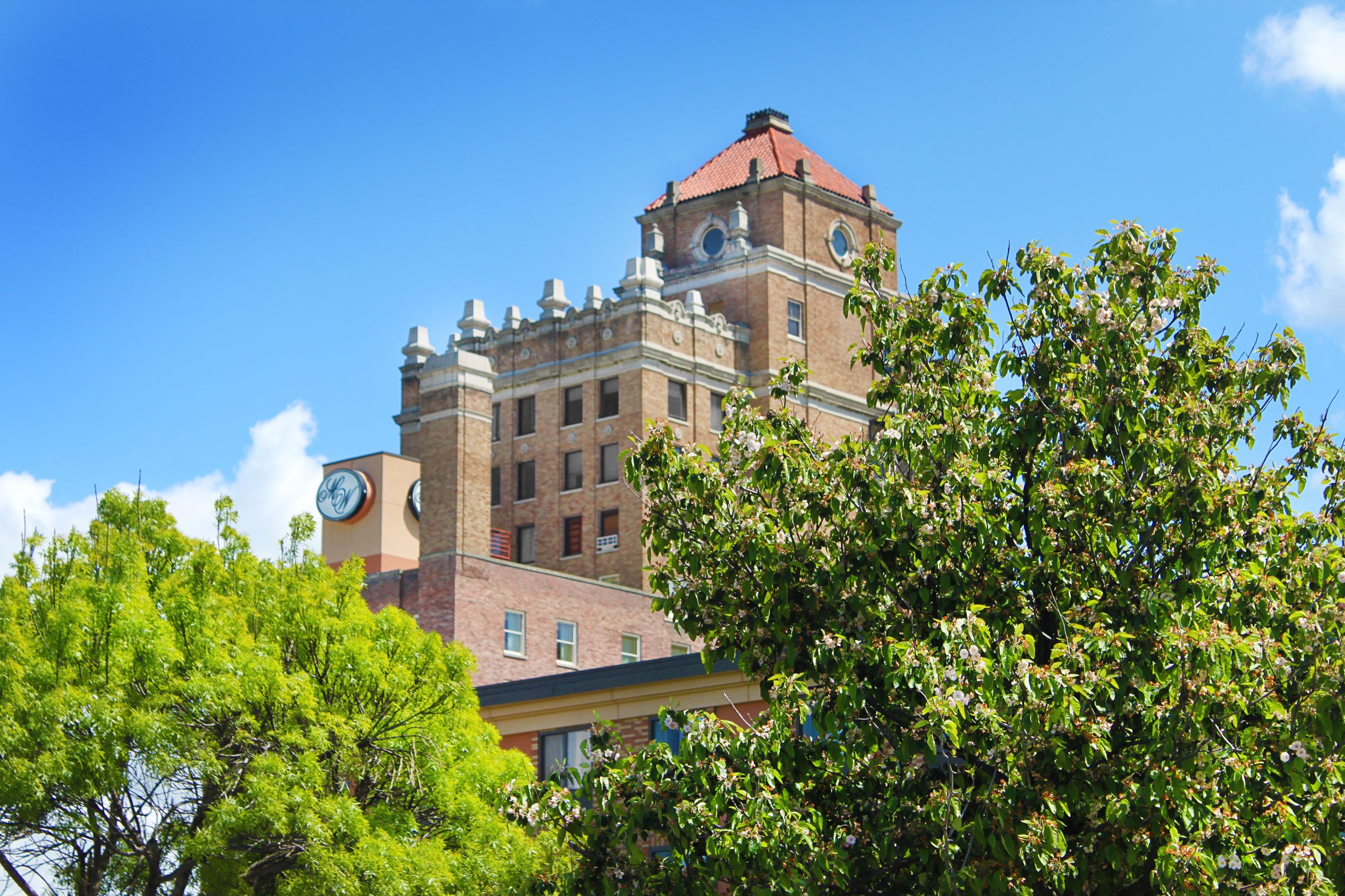 A historic building with a clock tower, large windows, and a prominent red roof.