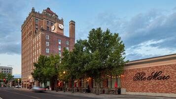 A historic building with a clock tower, a marquee sign, and trees along the street.