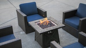 A patio with wicker furniture and a square fire pit.