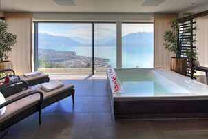 Uma área de spa com hidromassagem, assentos e vista para um lago e montanhas.