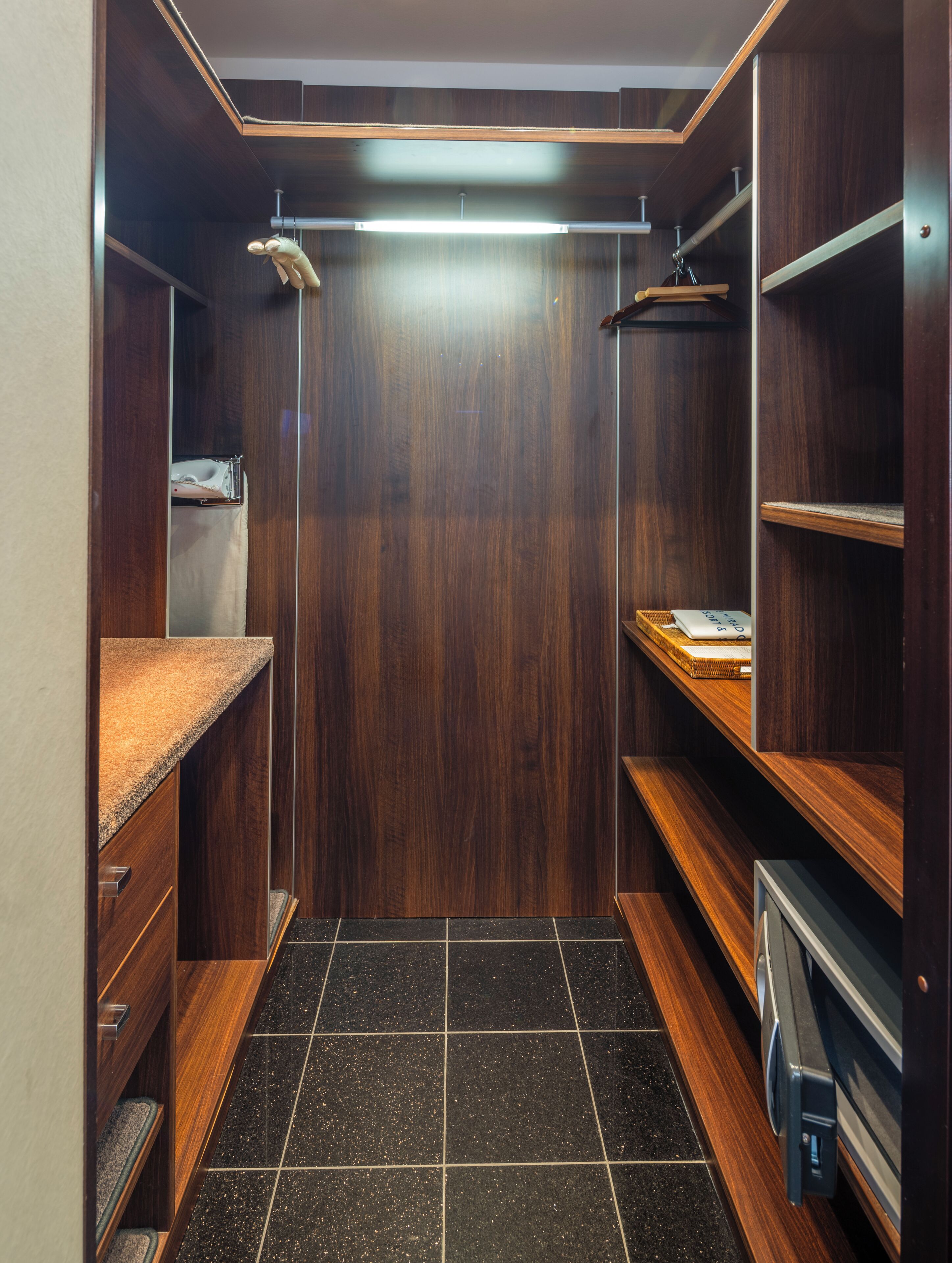 Un vestidor con estantes de madera, una encimera y suelo de baldosas.
