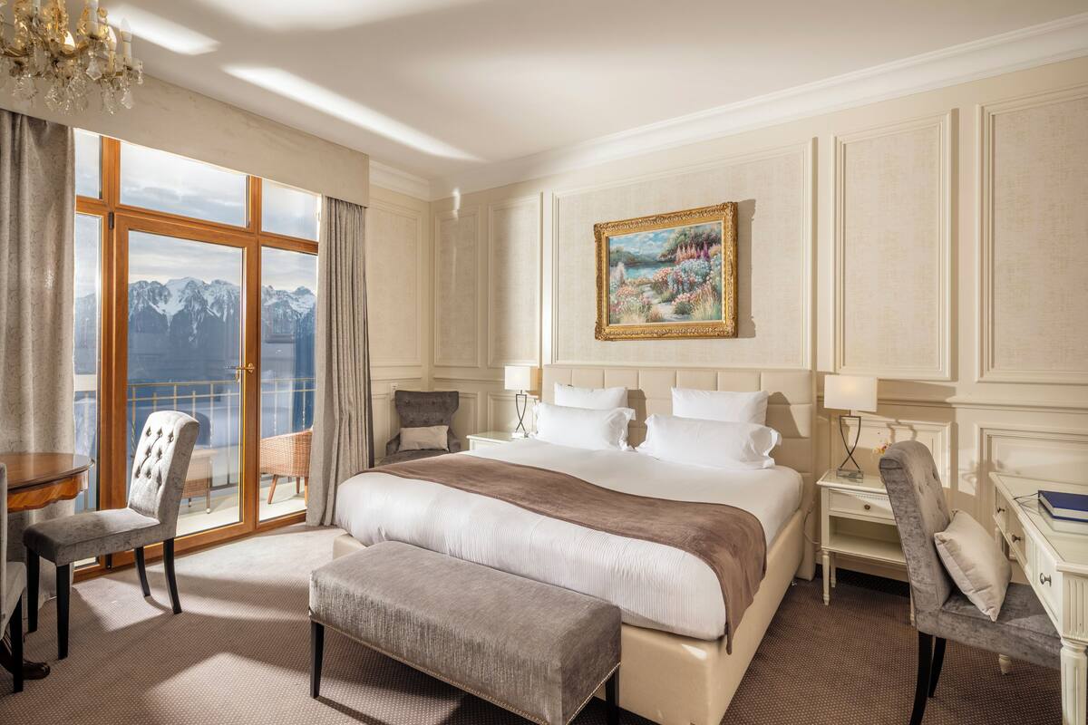 Ein geräumiges Schlafzimmer mit einem großen Bett, einem Sessel, einem Schreibtisch und einem Bild an der Wand.
