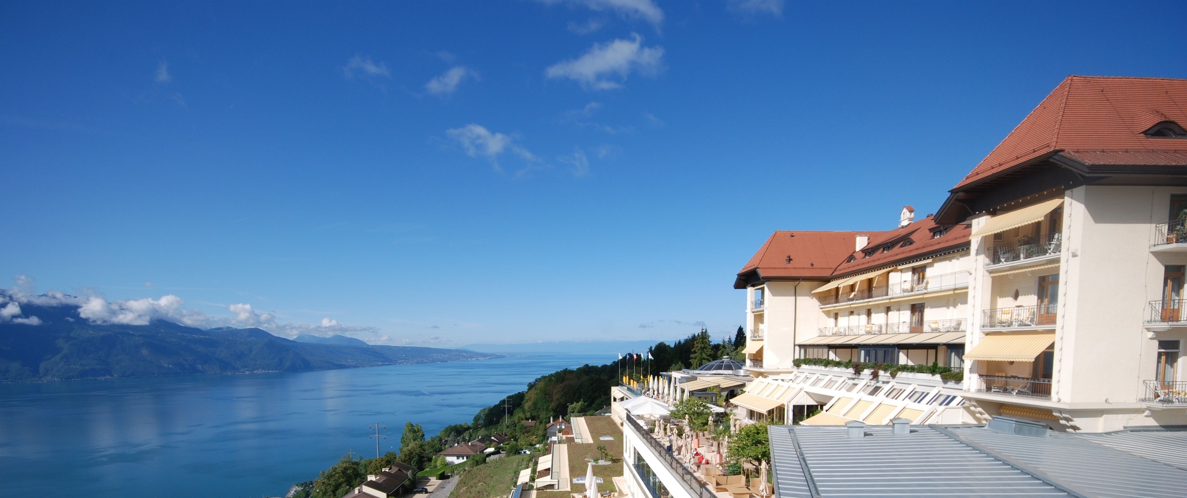 Een hotel met meerdere balkons met uitzicht op een meer en bergen.