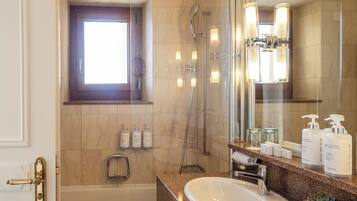 A bathroom with two sinks, a bathtub, a shower, a window, and a mirror.