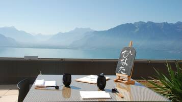 A table set with two black cups, a notebook, and a pen, with a chalkboard sign in the background.
