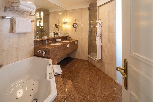 Un baño con bañera, dos lavamanos, cabina de ducha de vidrio y un perchero para toallas.
