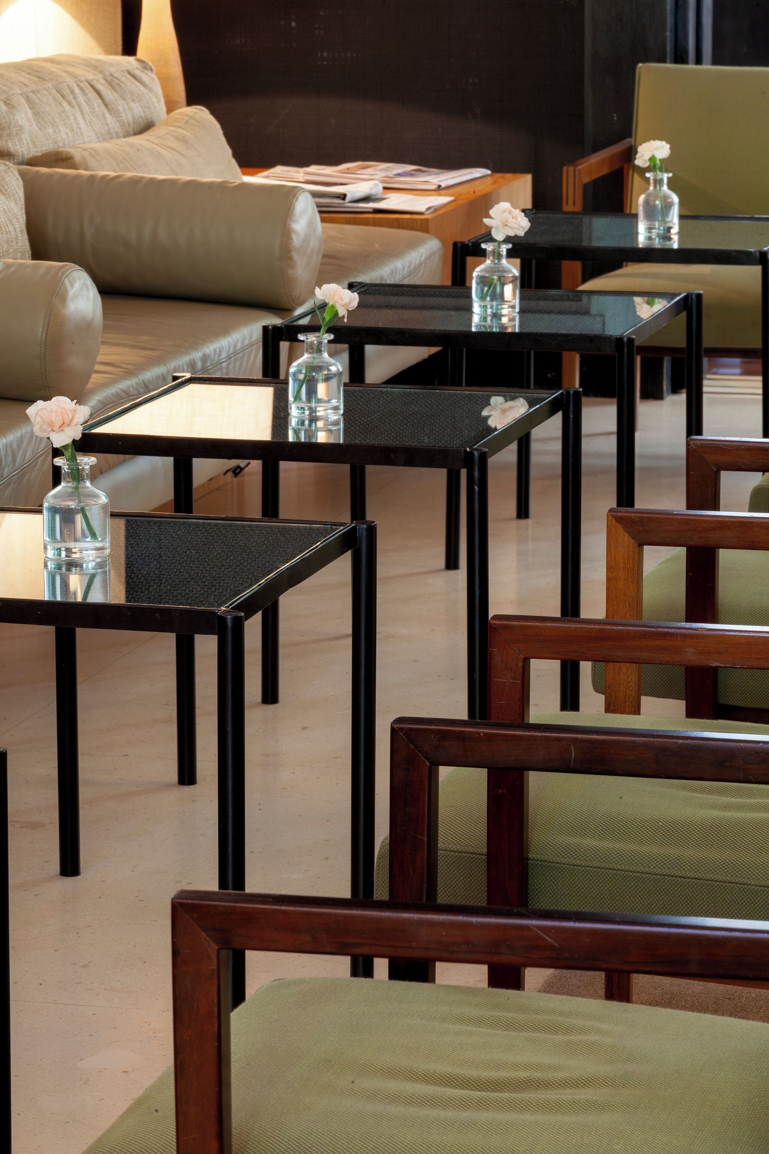 A modern hotel lobby with a sofa, multiple tables, and chairs.