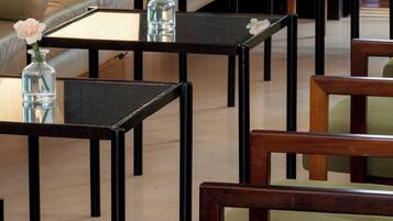 A modern hotel lobby with a sofa, multiple tables, and chairs.
