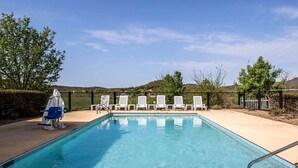 Una piscina con sillones de descanso y una zona de estar cubierta.