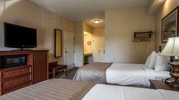 A hotel room with two beds, a television, a desk, and a lamp.