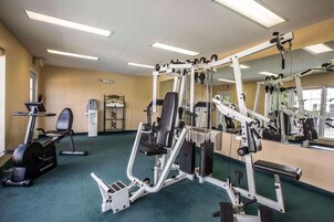A gym with exercise equipment, a mirrored wall, and a water dispenser.