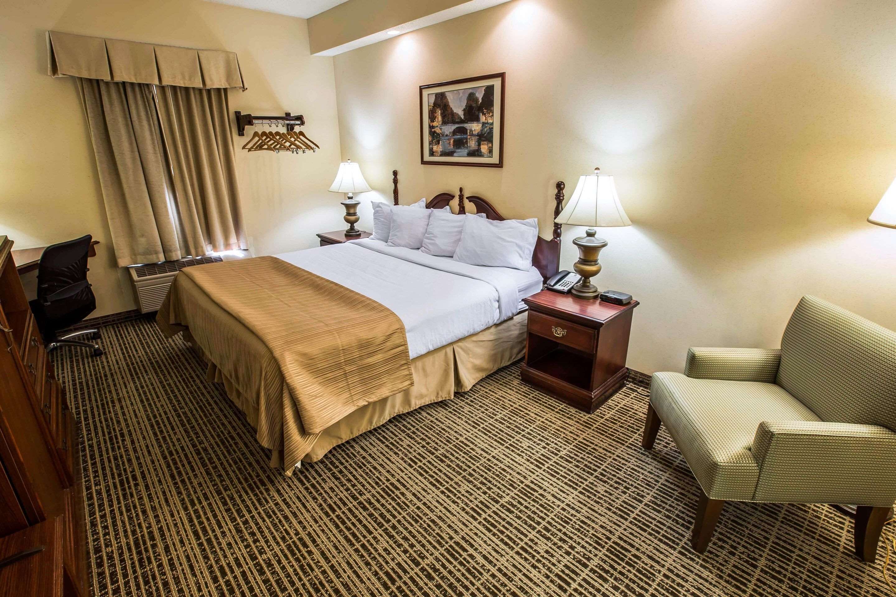 Une chambre d’hôtel comprenant un lit, des tables de chevet, une chaise, un bureau et un téléviseur.