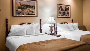 Una habitación de hotel con dos camas, una lámpara y dos cuadros enmarcados en la pared.