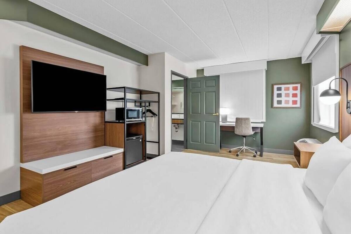 Une chambre d’hôtel équipée d’un lit, d’une télévision, d’un bureau et d’une armoire.