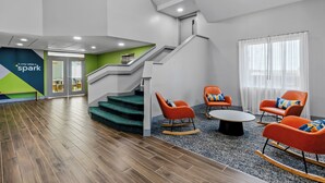 Un intérieur moderne avec un escalier, un coin salon et une porte visible donnant accès à une autre pièce.