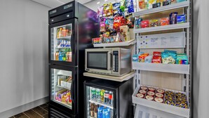 Un distributeur automatique de collations et de boissons, un four à micro-ondes et un réfrigérateur rempli de boissons.