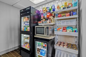 Máquina de vendas com lanches e bebidas, micro-ondas e frigorífico com bebidas.