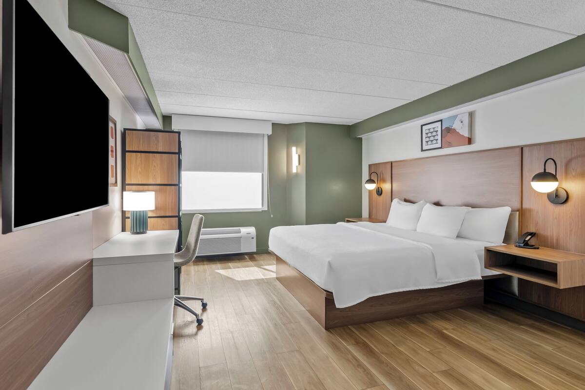Une chambre d’hôtel moderne équipée d’un lit, d’un bureau, d’une chaise et de lampes de chevet.