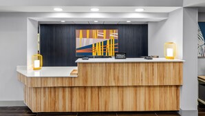 Un comptoir d’accueil avec un revêtement en bois, un tableau abstrait moderne et un panneau « Hilton ».