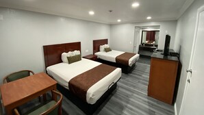 Ein Hotelzimmer mit zwei Betten, einem Schreibtisch, einem Stuhl und einem Fernseher.