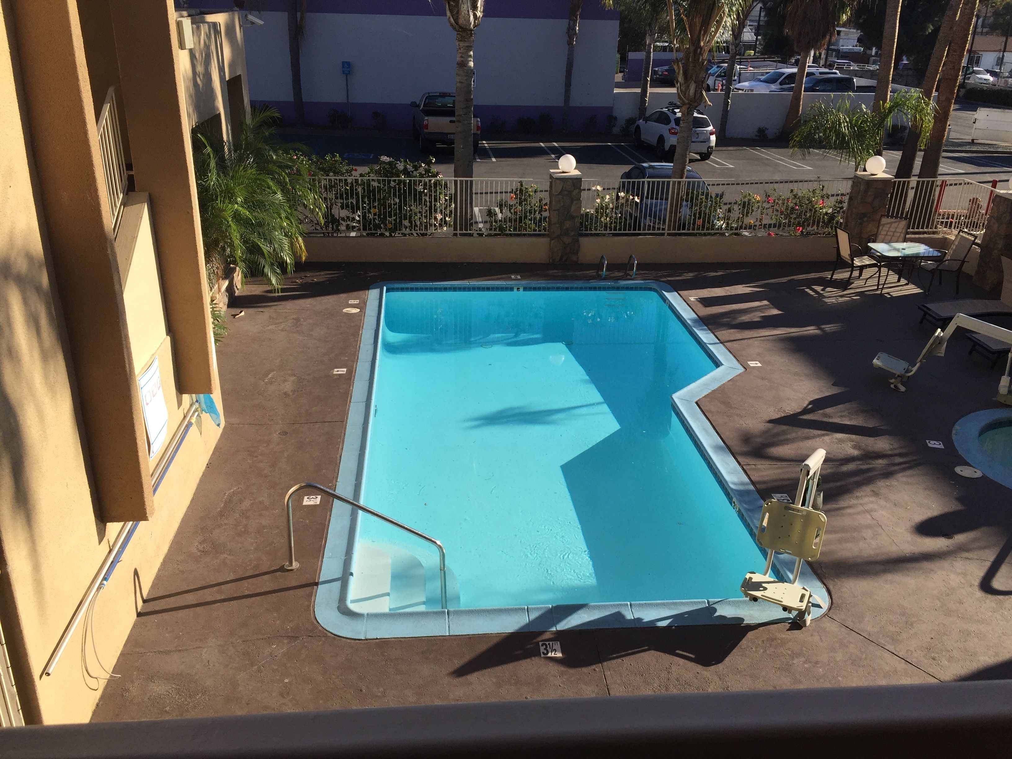 A rectangular swimming pool with a clear blue water surface, surrounded by a concrete deck.