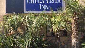 Une enseigne pour le Chula Vista Inn, avec un mur de pierre et des palmiers au premier plan.
