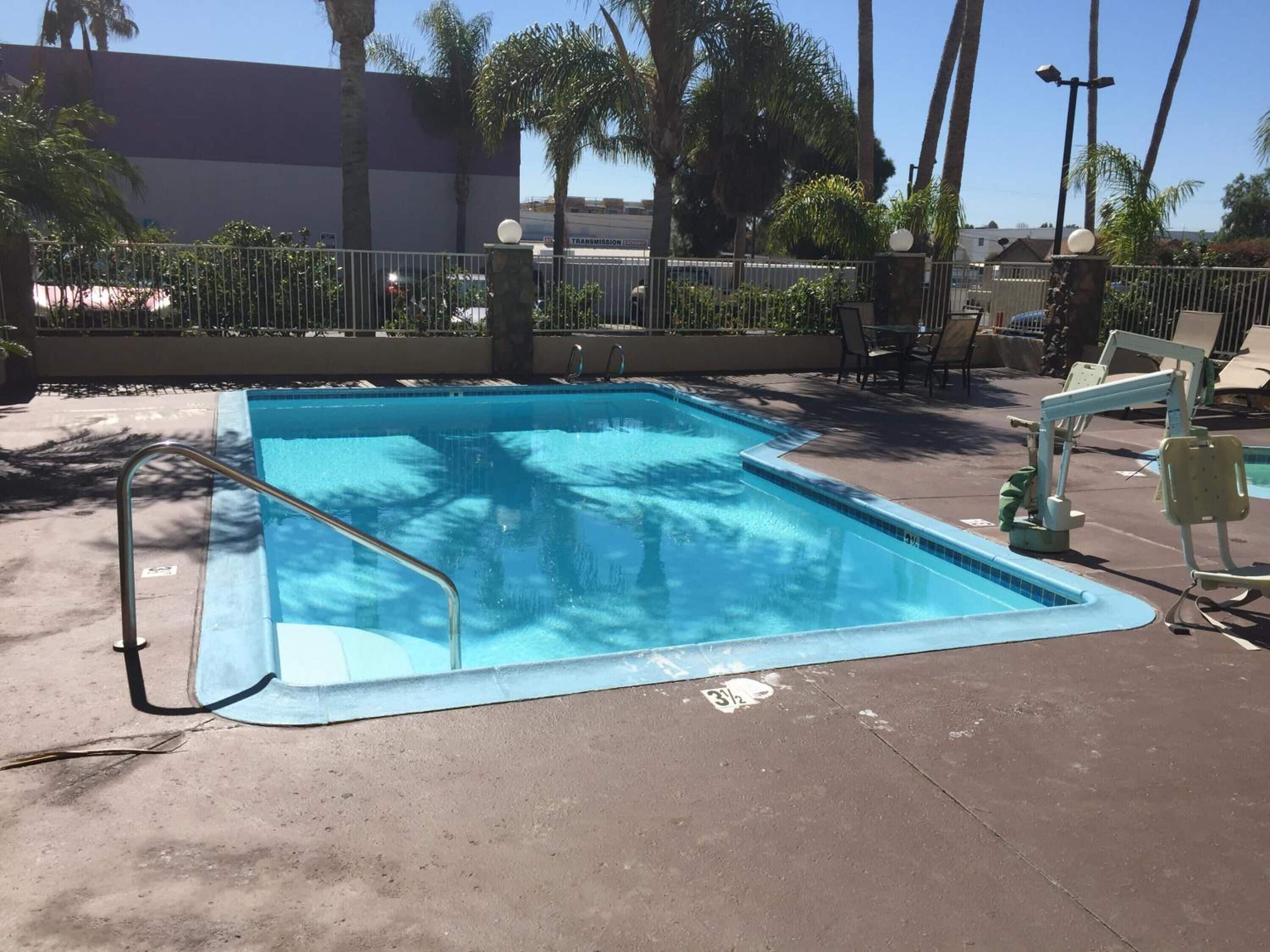 A rectangular pool with a metal ladder on one side, surrounded by a concrete deck.