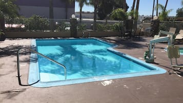 A rectangular pool with a metal ladder on one side, surrounded by a concrete deck.