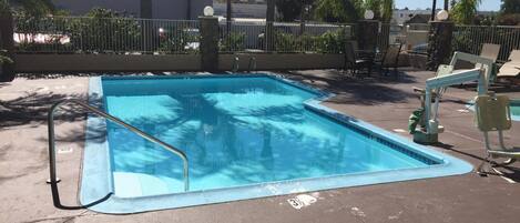 A rectangular pool with a metal ladder on one side, surrounded by a concrete deck.