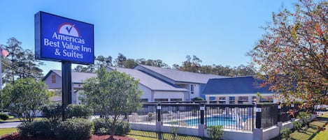 A sign for America's Best Value Inn & Suites with a swimming pool and fenced yard.