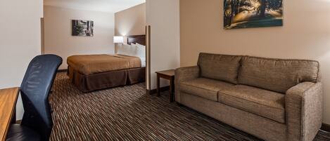 A hotel room with a bed, a sofa, a desk, and a chair.