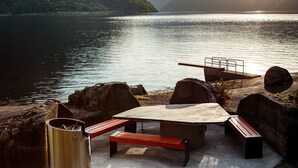 Un espace de pique-nique au bord du lac, équipé d’une table, de bancs et d’un barbecue.