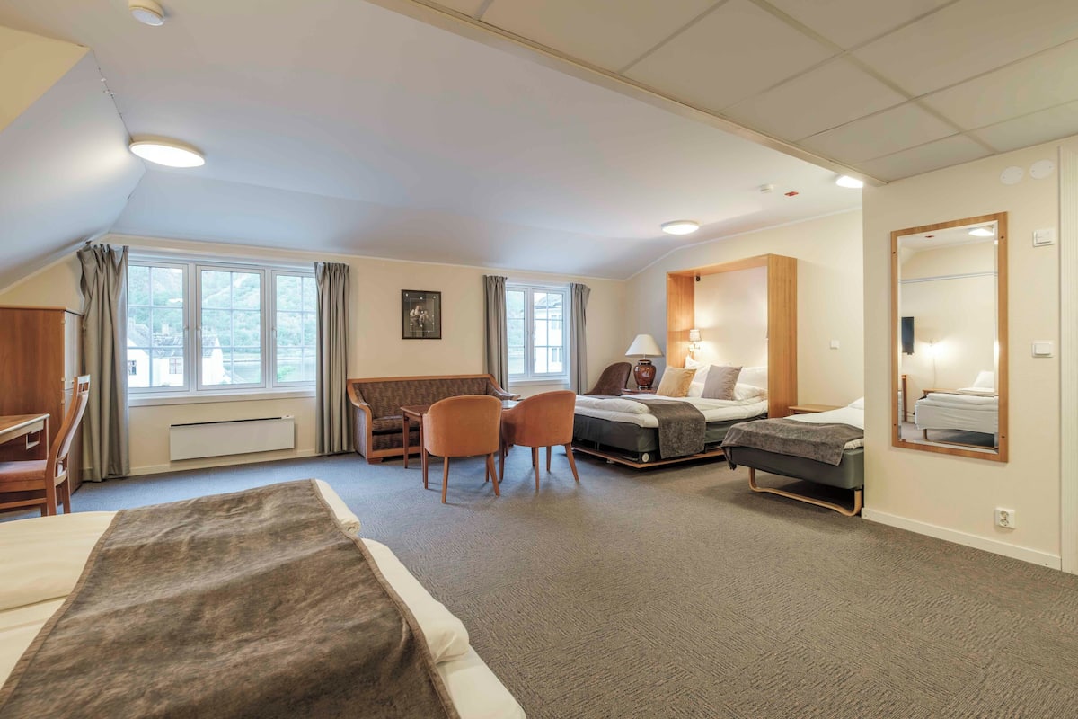 Une chambre d’hôtel comprenant un lit, un bureau, une chaise, un canapé, une petite table et une fenêtre.