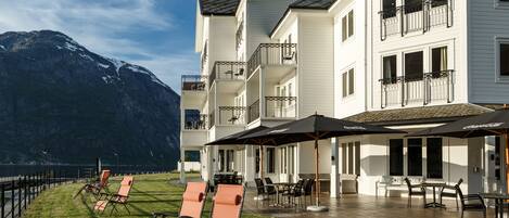 A hotel with outdoor seating, a pool, and mountain views.