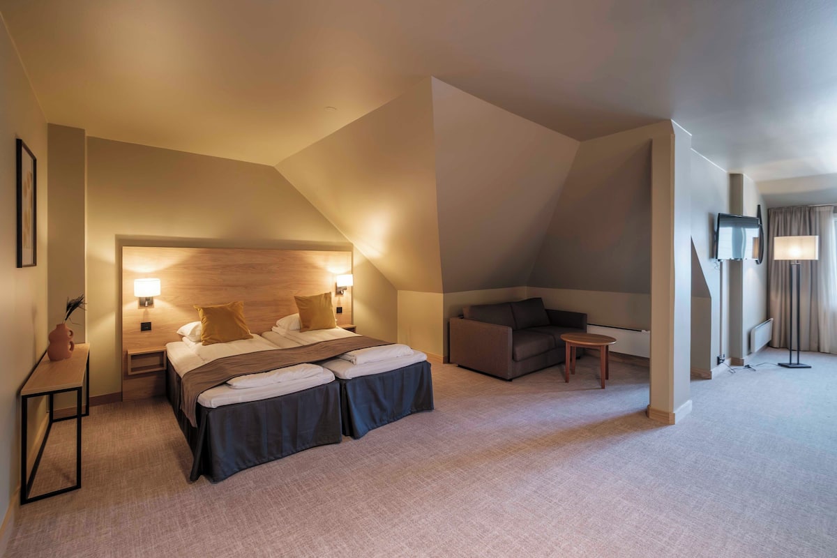 Une chambre d’hôtel avec un lit, un canapé, une petite table et une lampe.