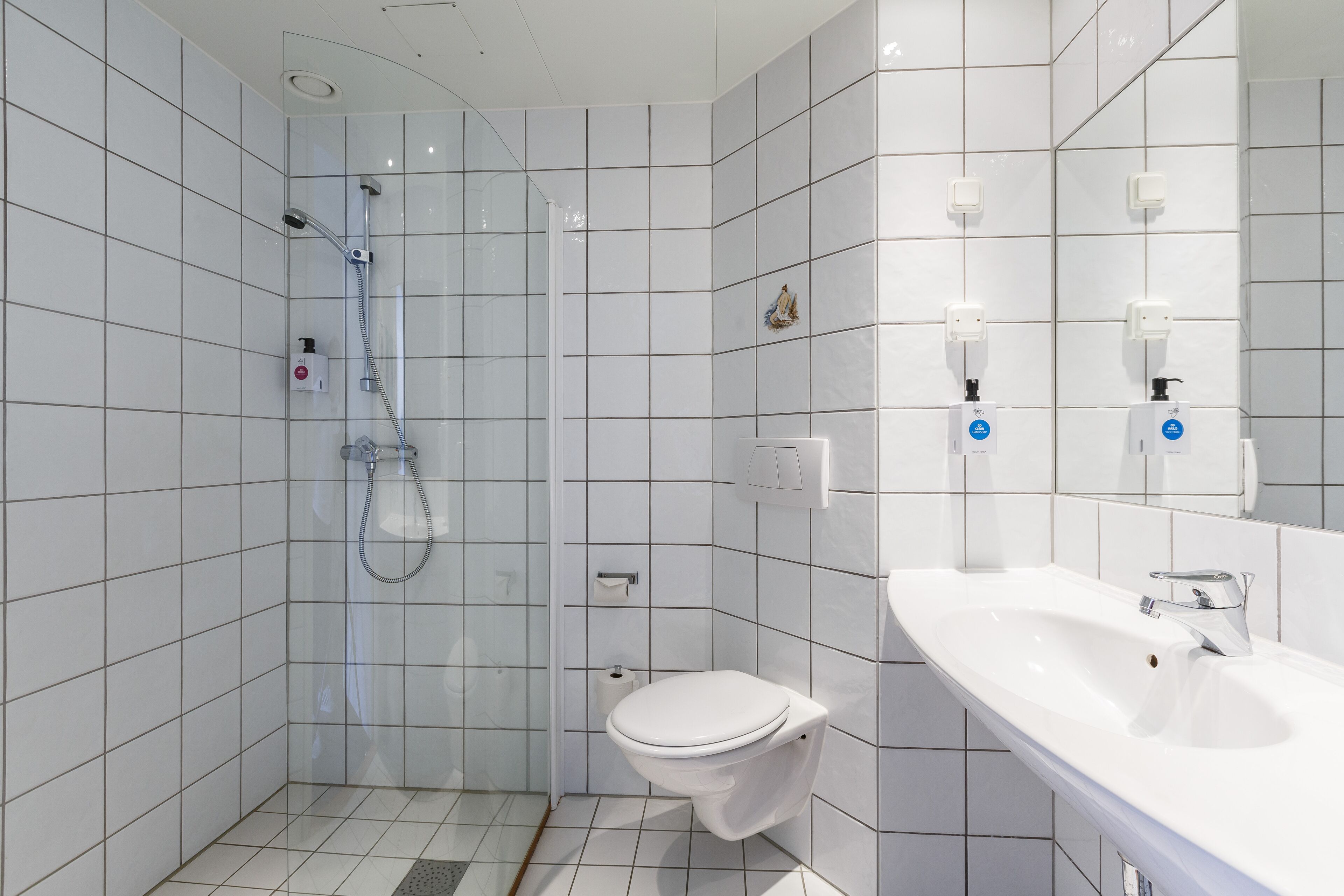 A modern bathroom with a glass-enclosed shower, a white toilet, and a sink with a mirror.