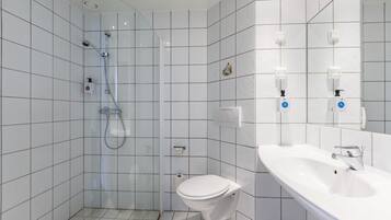 Ein modernes Badezimmer mit einer gläsernen Dusche, einer weißen Toilette und einem Waschbecken mit Spiegel.