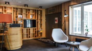 A modern reception area with a wooden reception desk, a television, and a seating area with two chairs and a small table.