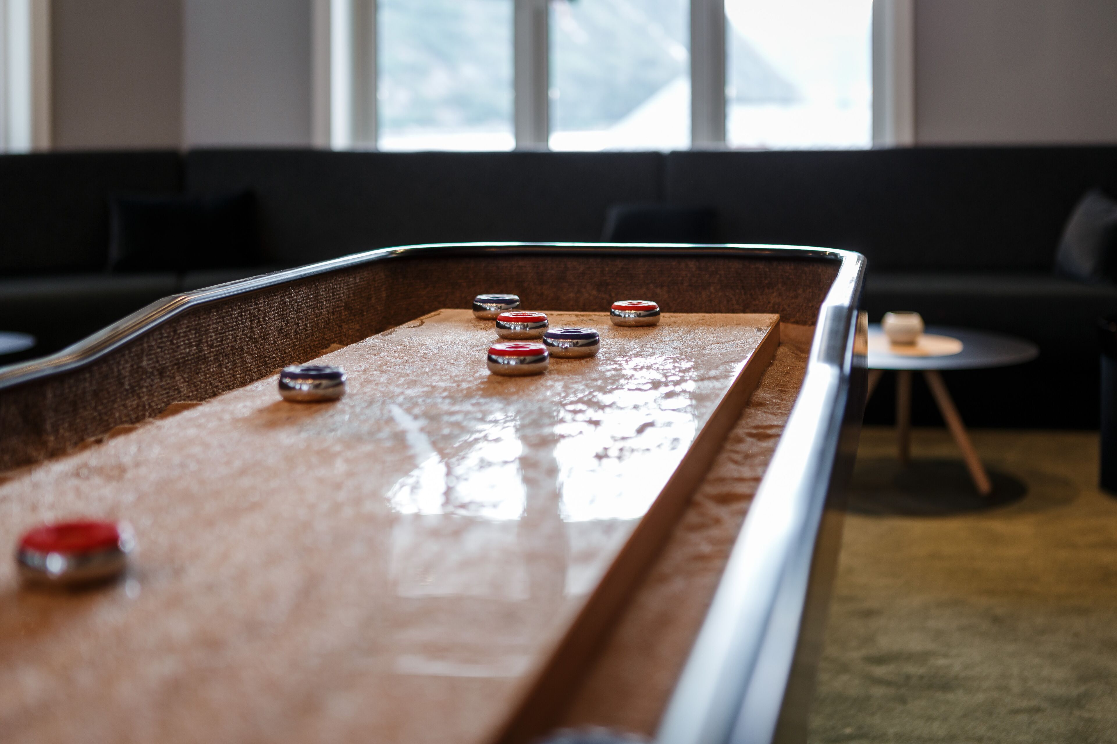 A pool table in a room with a sofa and a small table in the background.