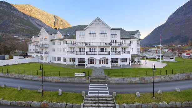 Un grand bâtiment blanc doté de nombreux balcons, d’une boutique de souvenirs et offrant une vue sur les montagnes.