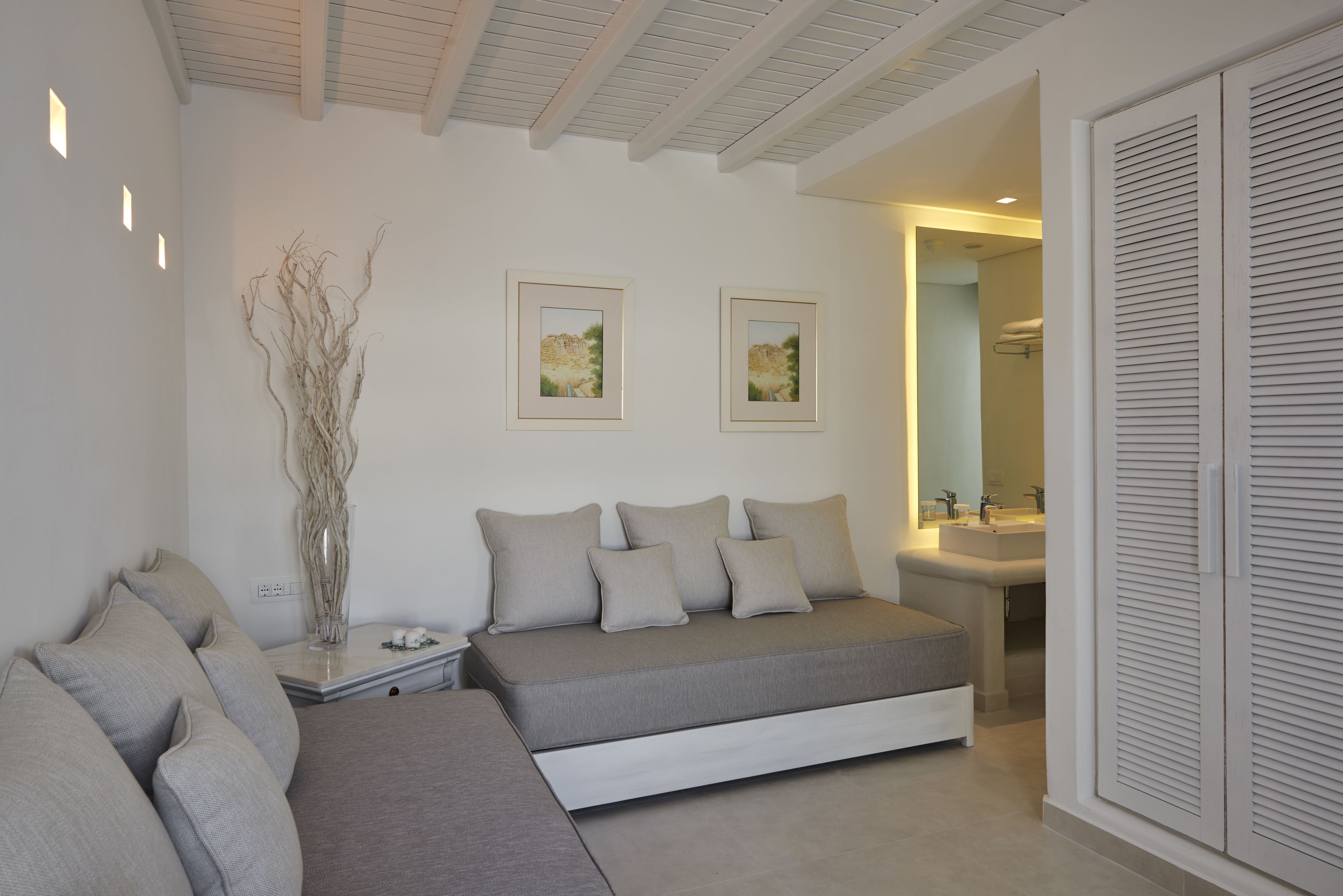 A modern bedroom with a sofa bed, bedside tables, a mirror, and a bathroom visible through an open door.