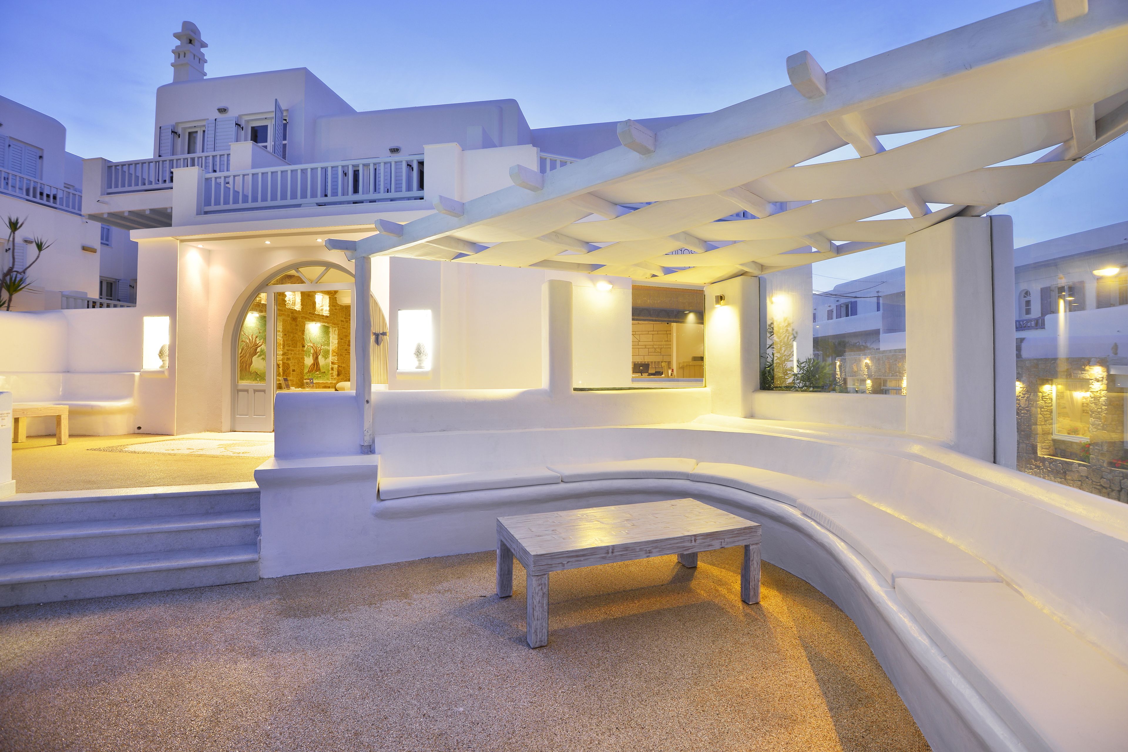 A modern outdoor seating area with a curved bench, a pergola, and a stone fireplace.
