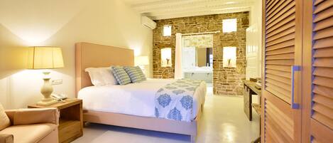 Un dormitorio con cama, mesita de noche, lámpara y pared de piedra.