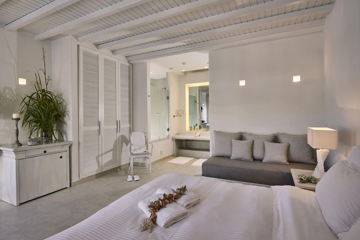 A modern bedroom with a large bed, a sofa, a desk, and a chair.