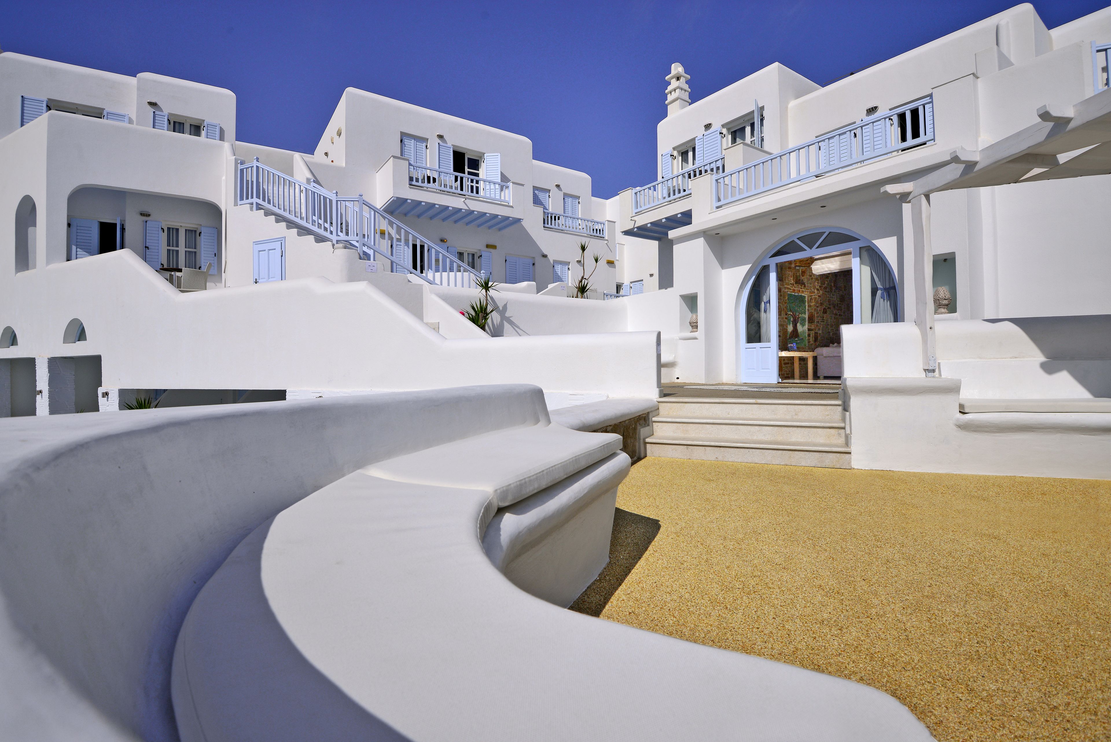 Un edificio blanco con balcones azules y una estructura blanca curva al frente.