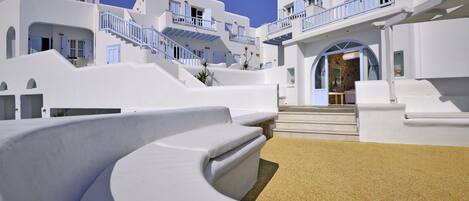 Un edificio blanco con balcones azules y una estructura blanca curva al frente.