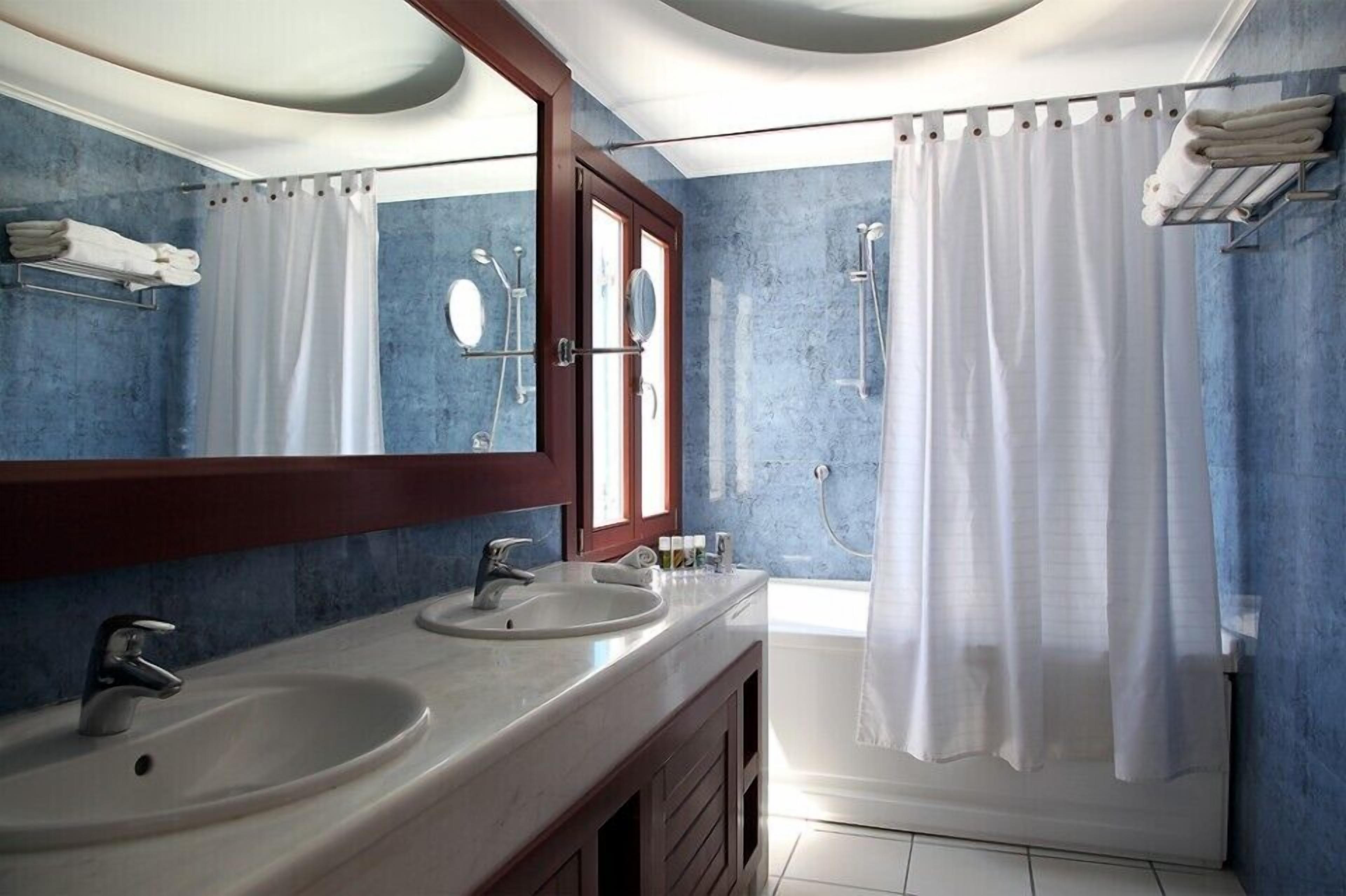 A bathroom with two sinks, a large mirror, and a shower area.