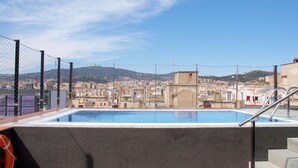 Una piscina en la azotea con vistas a la ciudad, un flotador salvavidas y una escalera.